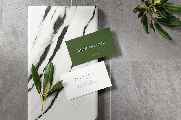 Clean minimal business card mockup on marble plate with leaves