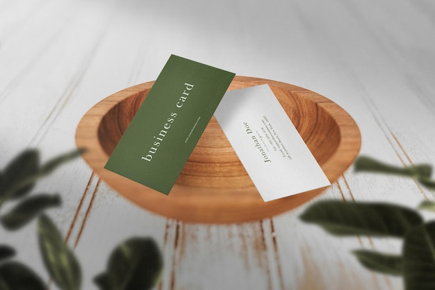 Clean minimal business card mockup on wooden bowl with leaves