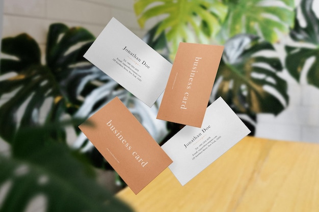 Clean minimal business cards mockup floating on top with leaves background. PSD file.