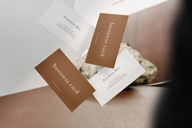 Clean minimal business cards mockup floating on wooden top with mirror background PSD file