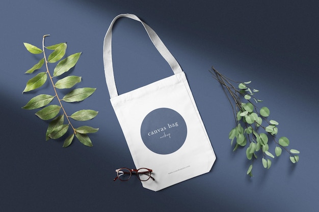 Clean minimal canvas bag mockup with leave and glasses on blue ocean background