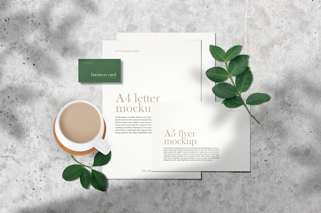 Clean minimal corporate documents mockup on grey table with green leaves shadow.