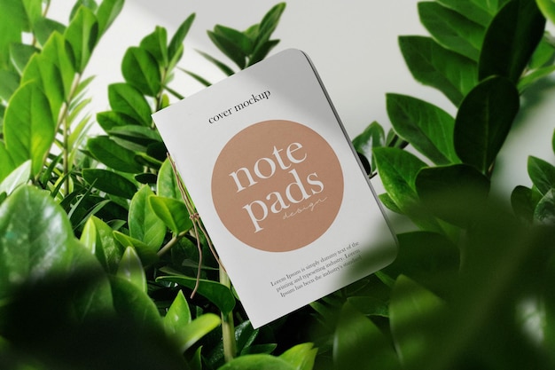 Clean minimal cover notepads mockup floating on leaves background. PSD file.