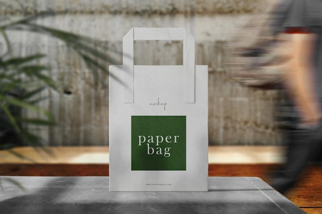 Clean minimal paper bag mockup standing on bench with people walking blur