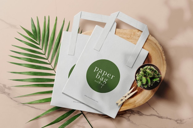 Clean minimal paper bag mockup on wooden plate with plant and leaves background PSD file