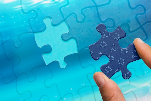 Close-up man holding jigsaw piece of puzzle