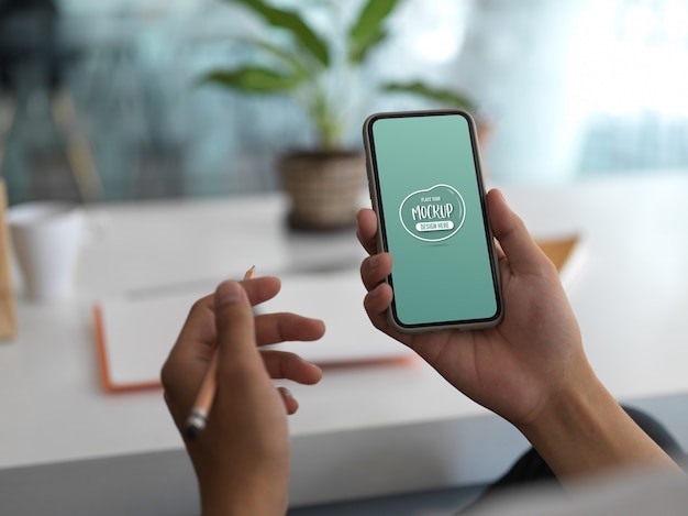 Close up view on hands holding smartphone with screen mockup