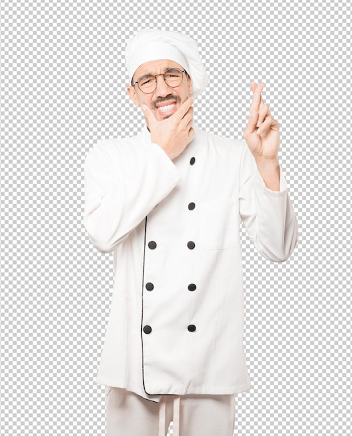 Concerned young chef doing a crossed fingers gesture