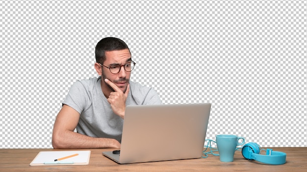 Confident young man with a gesture of doubt sitting at his desk