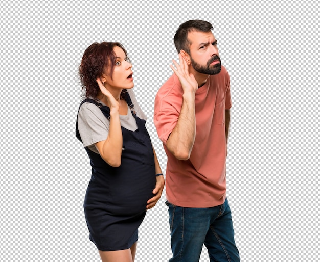 Couple with pregnant woman listening to something by putting hand on the ear