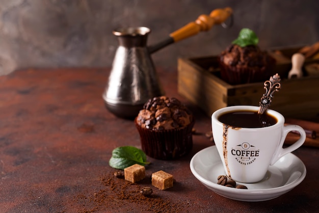 Cup of coffee with cooffee beans, wooden box with grains of coffee and spices, cupcake on a stone