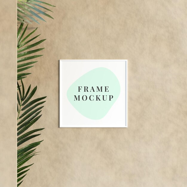 Decorative empty frame mockup hanging on the wall with plant in minimalist room