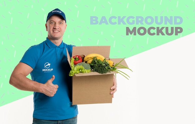 Delivery man holding a box full of vegetables with background mock-up