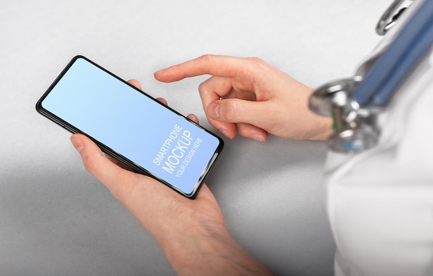 A doctor holds a smartphone with a screen that says mockup on it