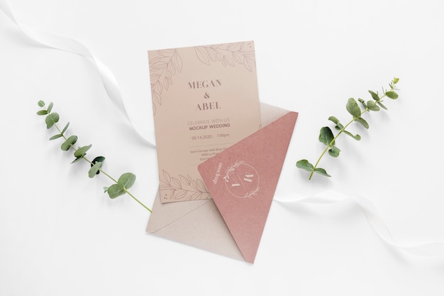 Fat lay of wedding card with envelope and plants