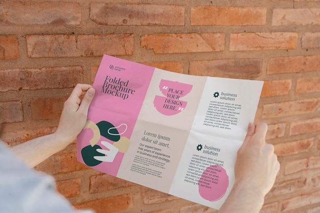 PSD female hands holding trifold brochure mock-up with abstract shapes