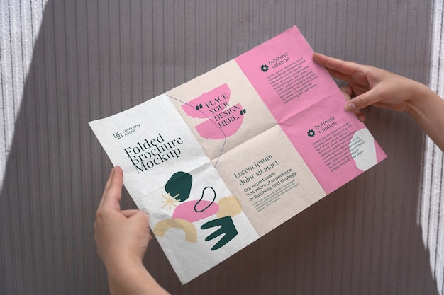 Female hands holding trifold brochure mock-up with abstract shapes