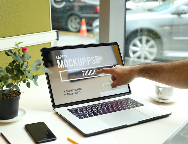 Finger touching to laptop in work space at office mockup PSD