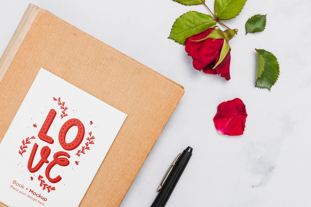 Flat lay of book with rose and pen