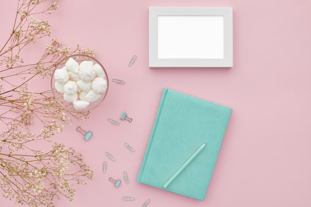 PSD flat lay flowers and a diary on pink table, top view. mockup