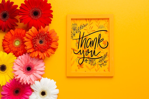 Flat lay of frame and flowers on yellow background