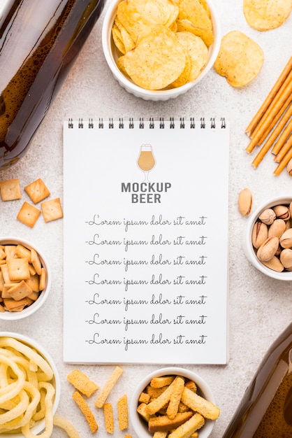 Flat lay of notebook with assortment of snacks and beer bottles