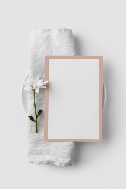 Flat lay of table arrangement with spring menu mock-up on towel and flower