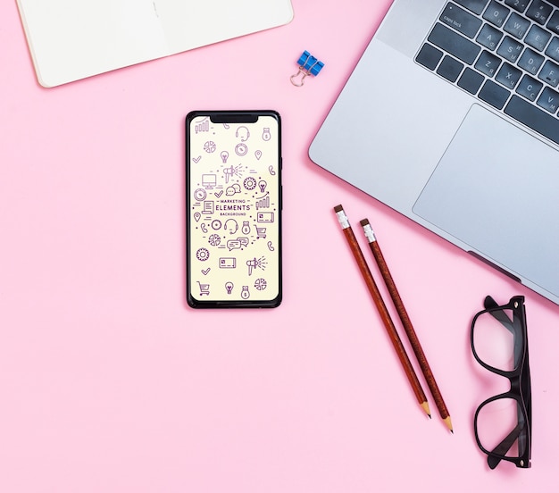 Flatlay with smartphone, pencils, glasses, laptop and notebook