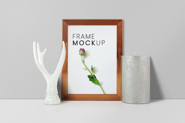 Frame on the table with statue and candle mockup