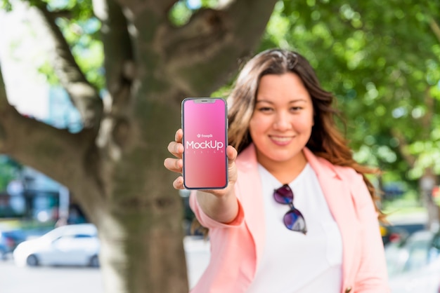 Friendly woman presenting smartphone mockup