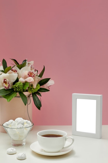 PSD front view blank mockup of photo frame. orchid flowers, cup of tea and sweets.