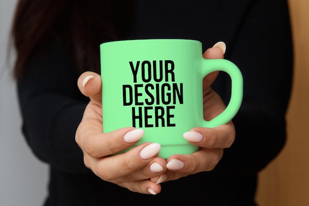 Green coffee mug mockup in the hands of a girl changeable color psd