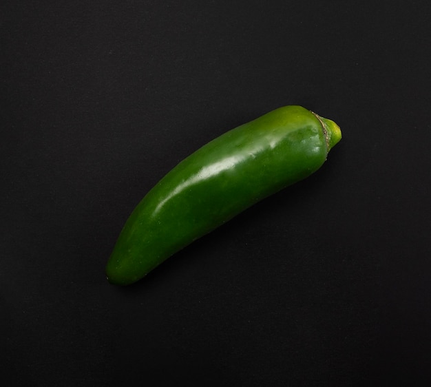 a green jalapeno on a black background