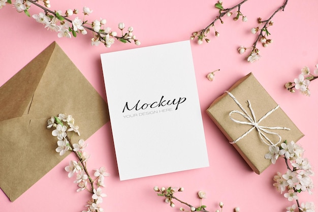 Greeting card mockup with gift box, envelope and cherry tree twigs with flowers