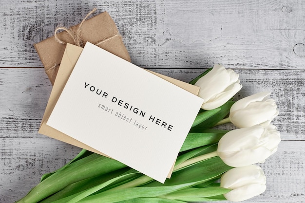 Greeting card mockup with tulip flowers and gift box on wooden