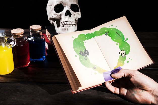 Hand holding book with drawings and bottles of poison