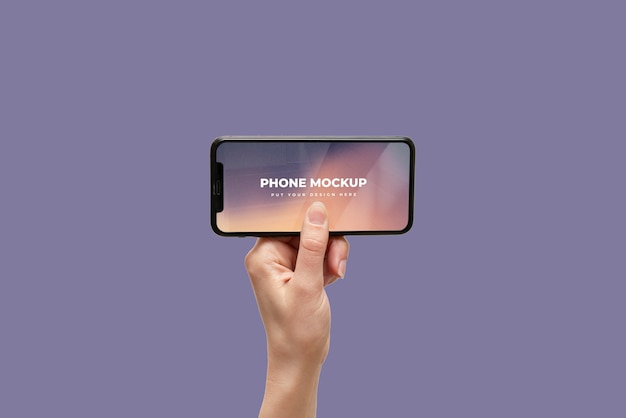 Hand holding smartphone device mock-up on color background