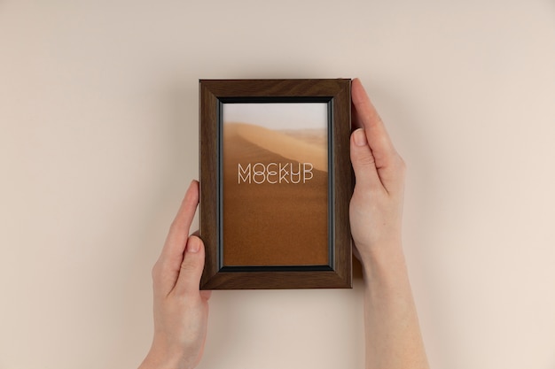 Hands holding wooden frame mockup top view