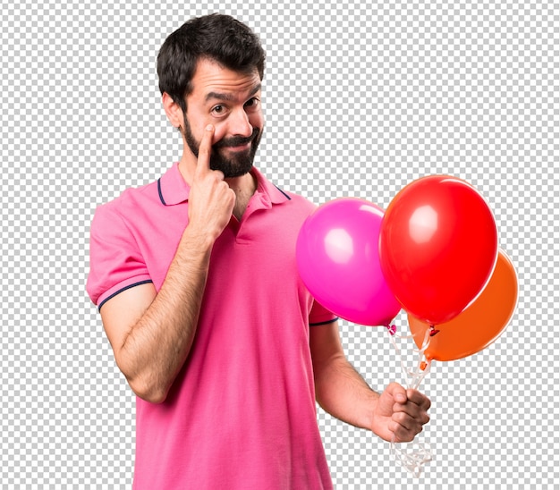 Handsome young man holding balloons and  showing something