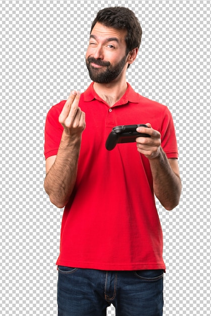 Handsome young man playing videogames making money gesture