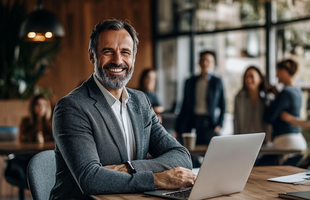 PSD happy businessman sitting at his desk with laptop and looking to camera while standing office worker