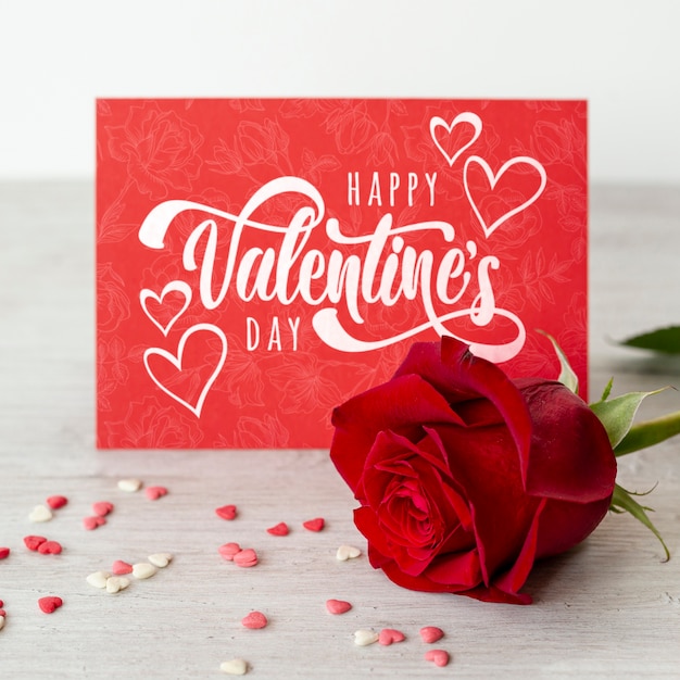 Happy valentines day lettering on red card with red rose