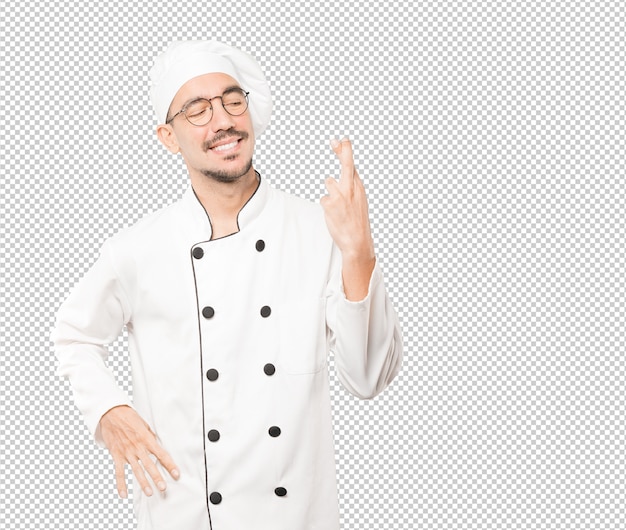 Happy young chef doing a crossed fingers gesture