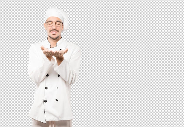 Happy young chef holding something with his hand