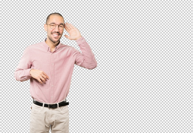 Happy young man smiling and making a gesture of trying to hear something