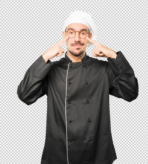 PSD hesitant young chef making a gesture of being careful with his hand pointing at his eye