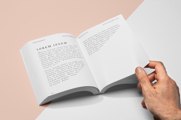 High angle hand holding page of open book mock-up