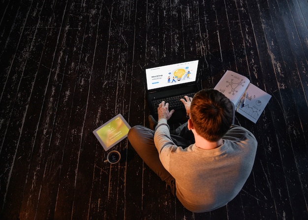 High angle of man working from home on laptop with coffee and copy space