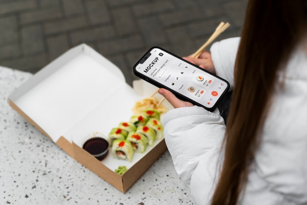 PSD high angle woman with smartphone and sushi