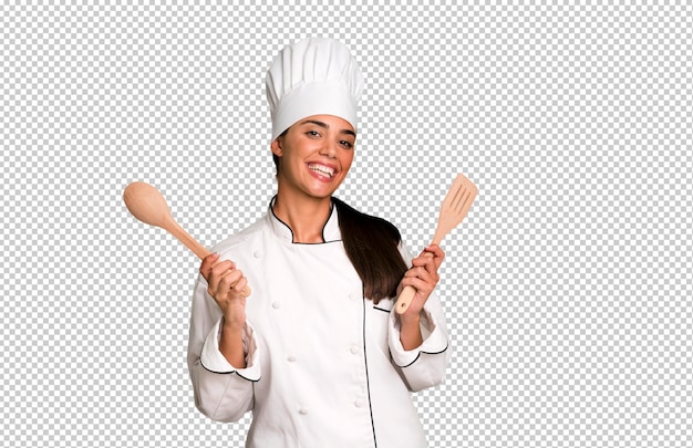 Hispanic pretty young adult and expressive chef woman with cook tools